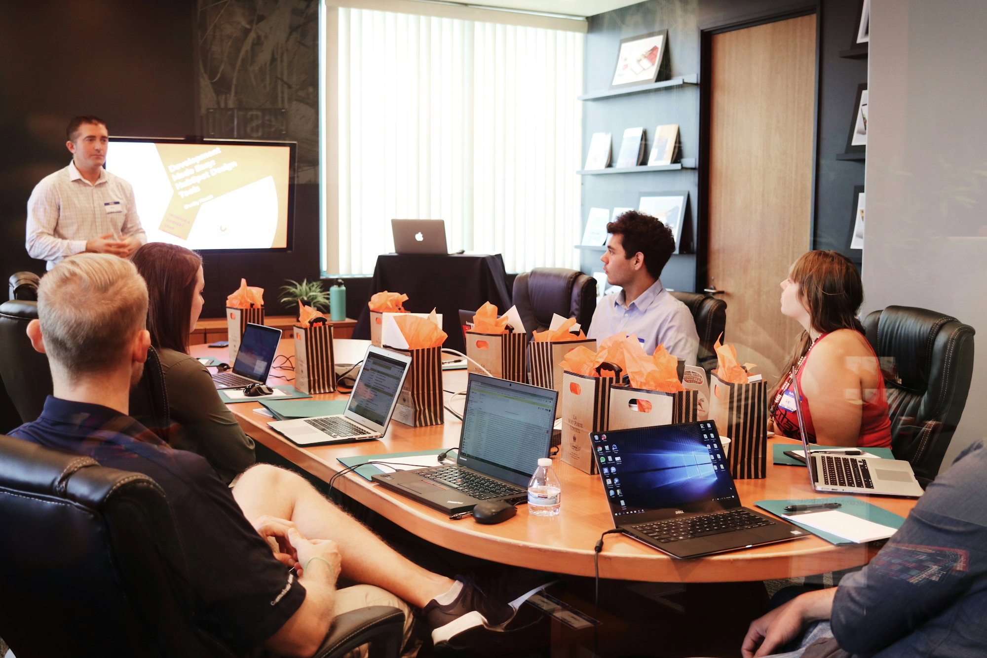man-standing-in-front-of-people-sitting-beside-table-with-laptop-computers.jpg man standing in front of people sitting beside table with laptop computers